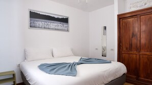 A bedroom with a bed, a wooden wardrobe, a mirror, and a framed picture on the wall. - Sea Waves - 500M from the beach, Pool and Terrace By LVH (Puerto del Carmen)