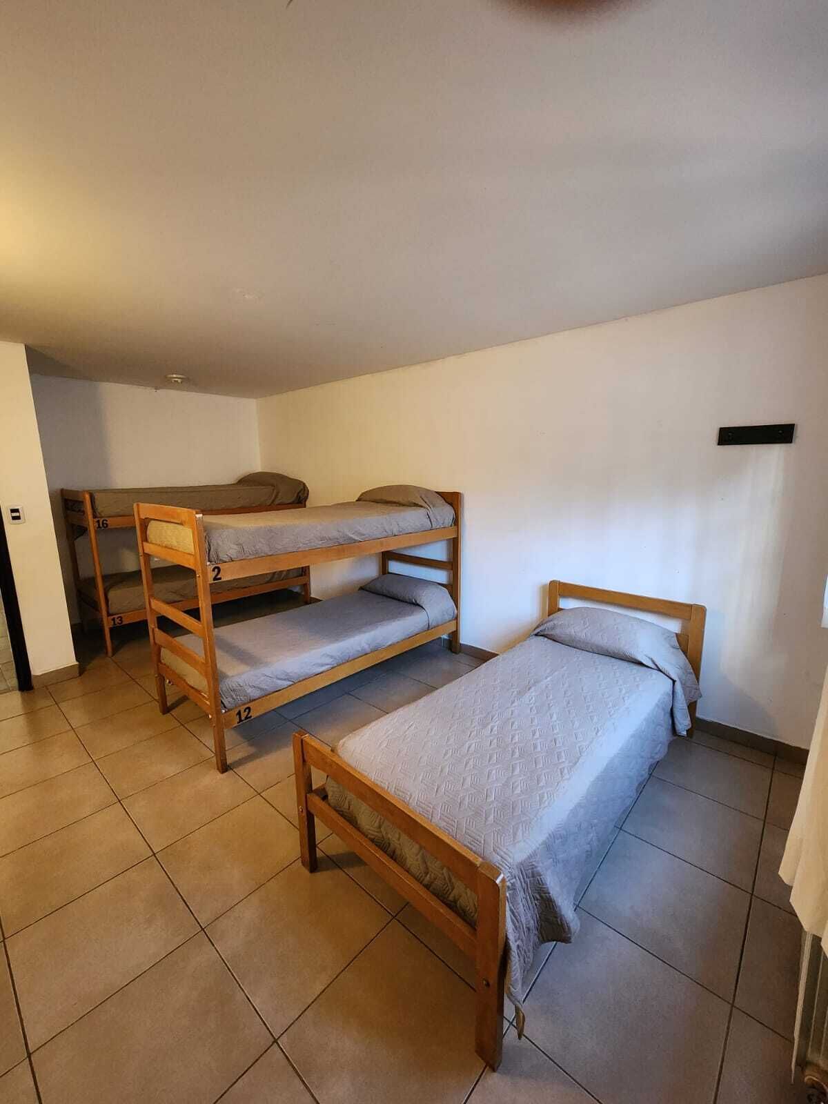 A dormitory room with bunk beds, a small desk, and a tiled floor.