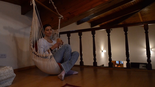 A person sitting in a hammock in a room with wooden beams and a staircase. - Anum Hostel (Ushuaia)