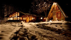 A snow-covered landscape with two wooden cabins. - Anum Hostel (Ushuaia)