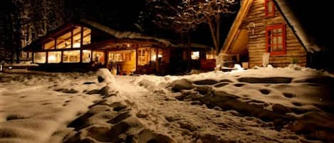 A snow-covered landscape with two wooden cabins.