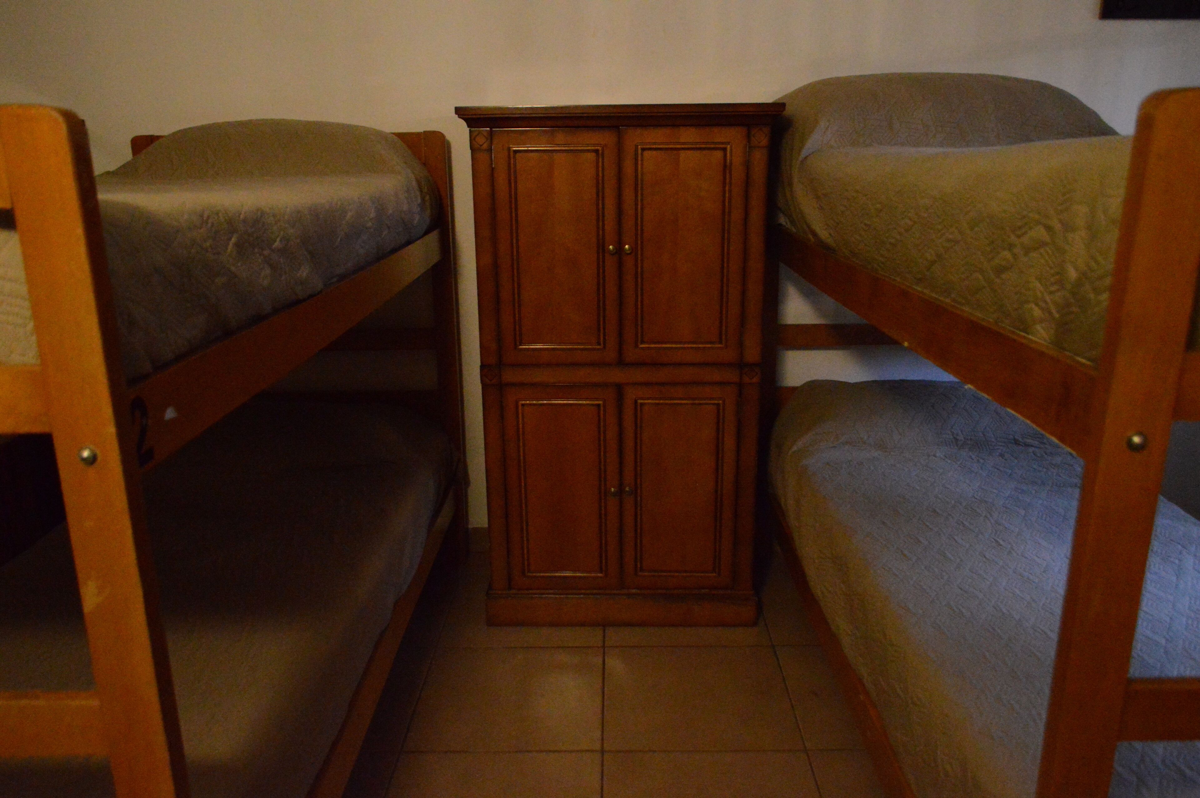 A small room with two bunk beds and a wooden cabinet.