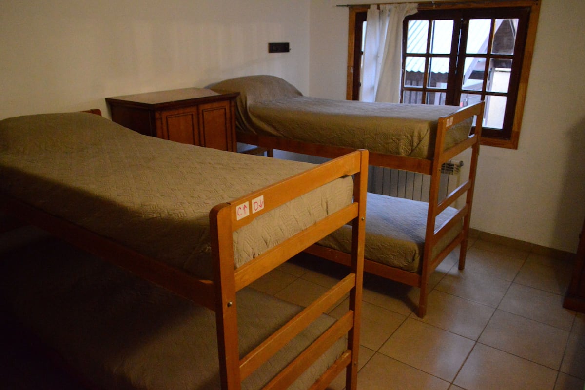 A room with two bunk beds, a window with curtains, and a radiator.