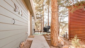 A wooden cabin with a concrete pathway leading to a covered outdoor seating area. - Cozy 1BR Chalet | Pikes Peak, Grill & Relaxing Patio (Woodland Park)