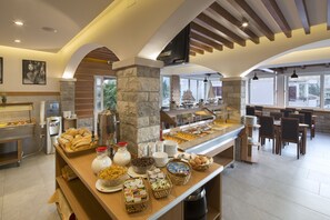 Uma área de buffet com diversos tipos de comida e um espaço de refeições com mesas e cadeiras.