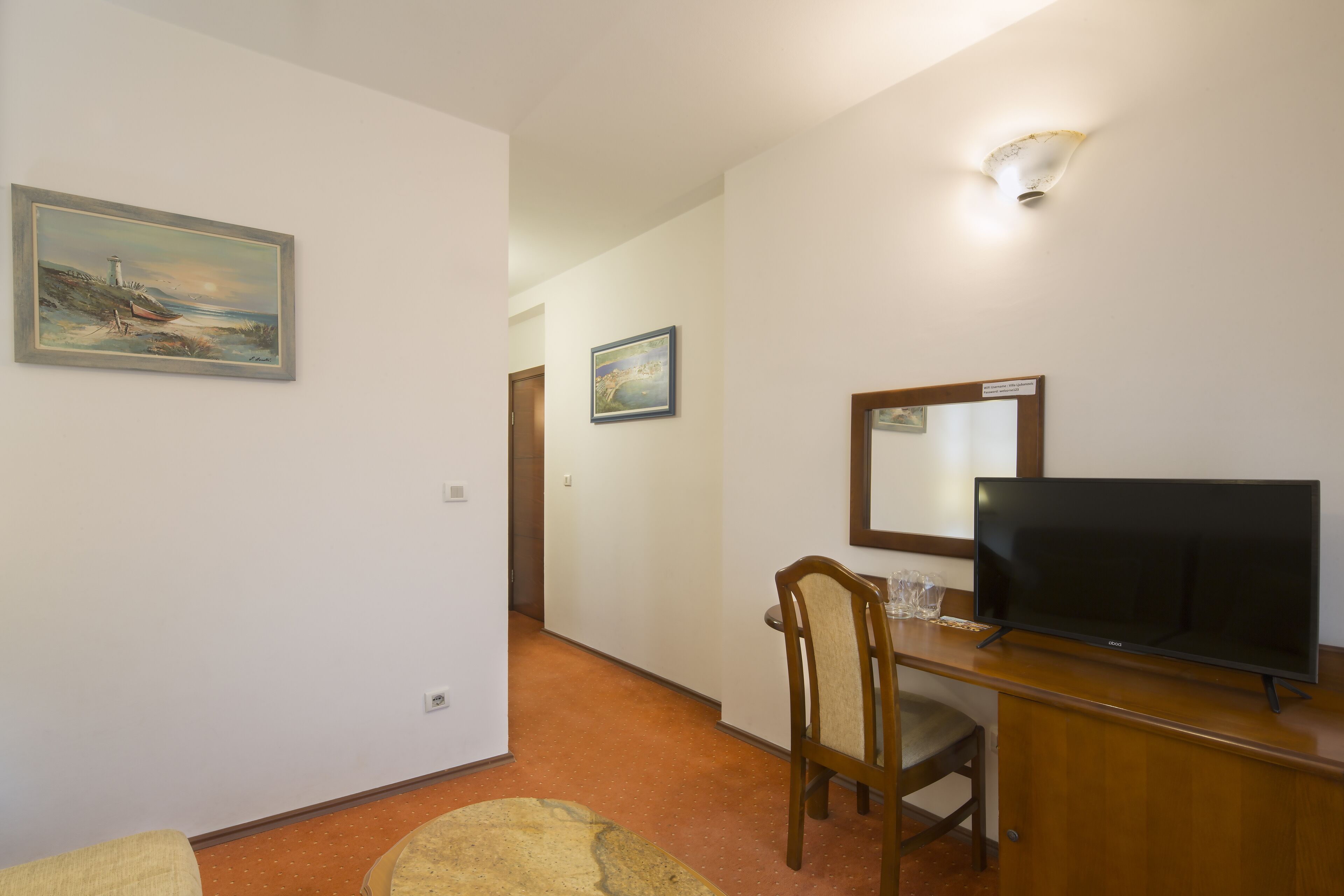 Ein Hotelzimmer mit einem Holztisch, einem Fernseher und zwei gerahmten Bildern an den Wänden.