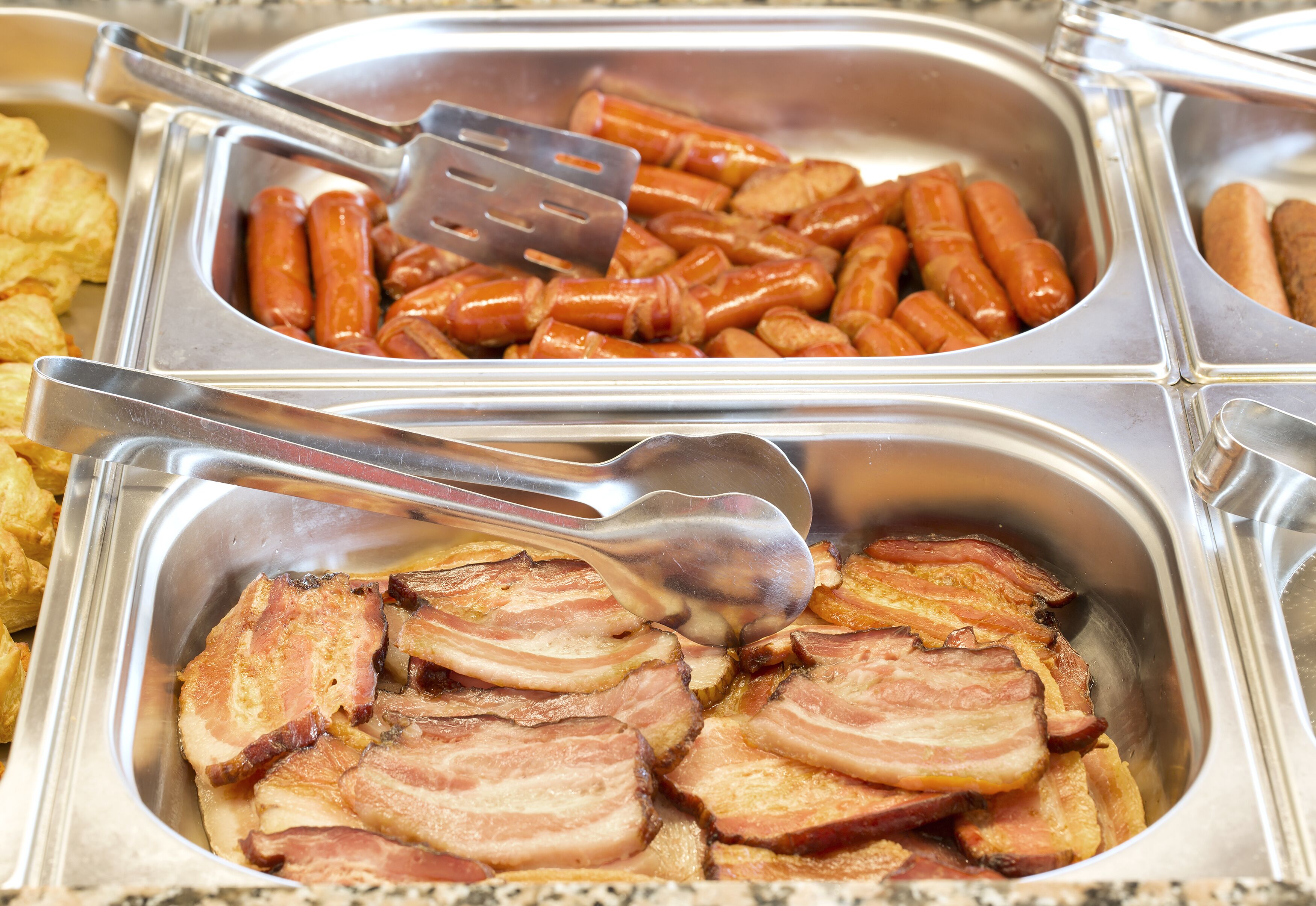 Un bufé con diversas opciones de comida, incluyendo salchichas y tocino.