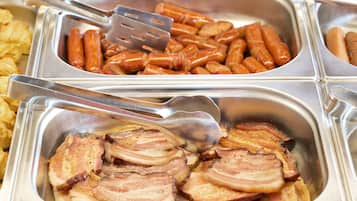Un bufé con diversas opciones de comida, incluyendo salchichas y tocino.
