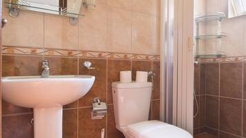 Un baño con lavamanos, inodoro y ducha.