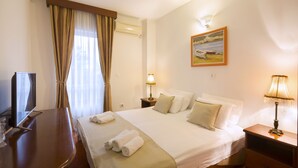Una habitación de hotel con cama, televisión, escritorio y un cuadro en la pared.