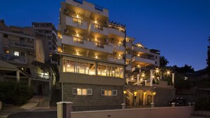 Un edificio residencial de varios pisos con balcones, fachada de piedra y una entrada bien iluminada.