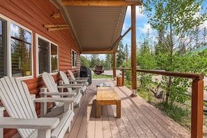 A wooden deck with Adirondack chairs and a table, overlooking a forested area. - Stanley Stays - The Valley Creek Cabin (Stanley)