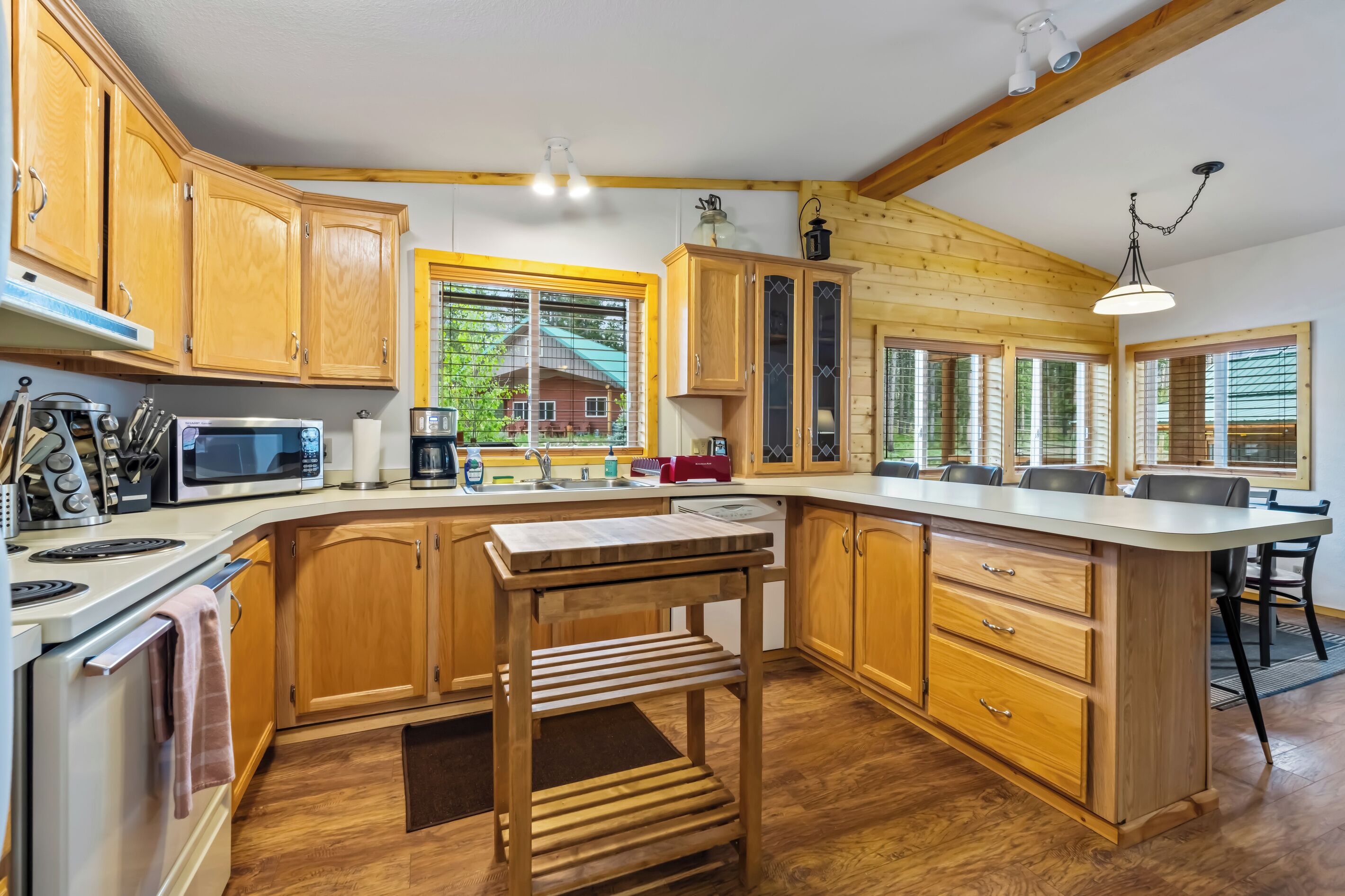 A modern kitchen with wooden cabinets, a built-in microwave, and a large island with a sink.