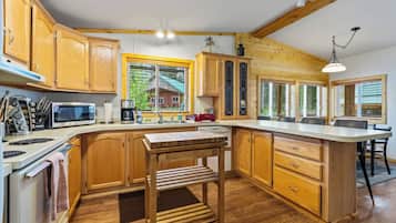 A modern kitchen with wooden cabinets, a built-in microwave, and a large island with a sink.