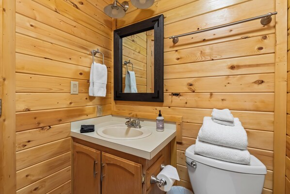 A wooden-paneled bathroom with a sink, mirror, towel rack, and toilet. - Stanley Stays - The Valley Creek Cabin (Stanley)