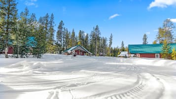 A snow-covered landscape with a red building and a windmill, surrounded by trees.