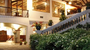 A hotel with a balcony, a staircase, and a garden area.