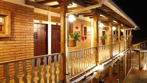 A wooden building with a balcony, brick walls, and potted plants.