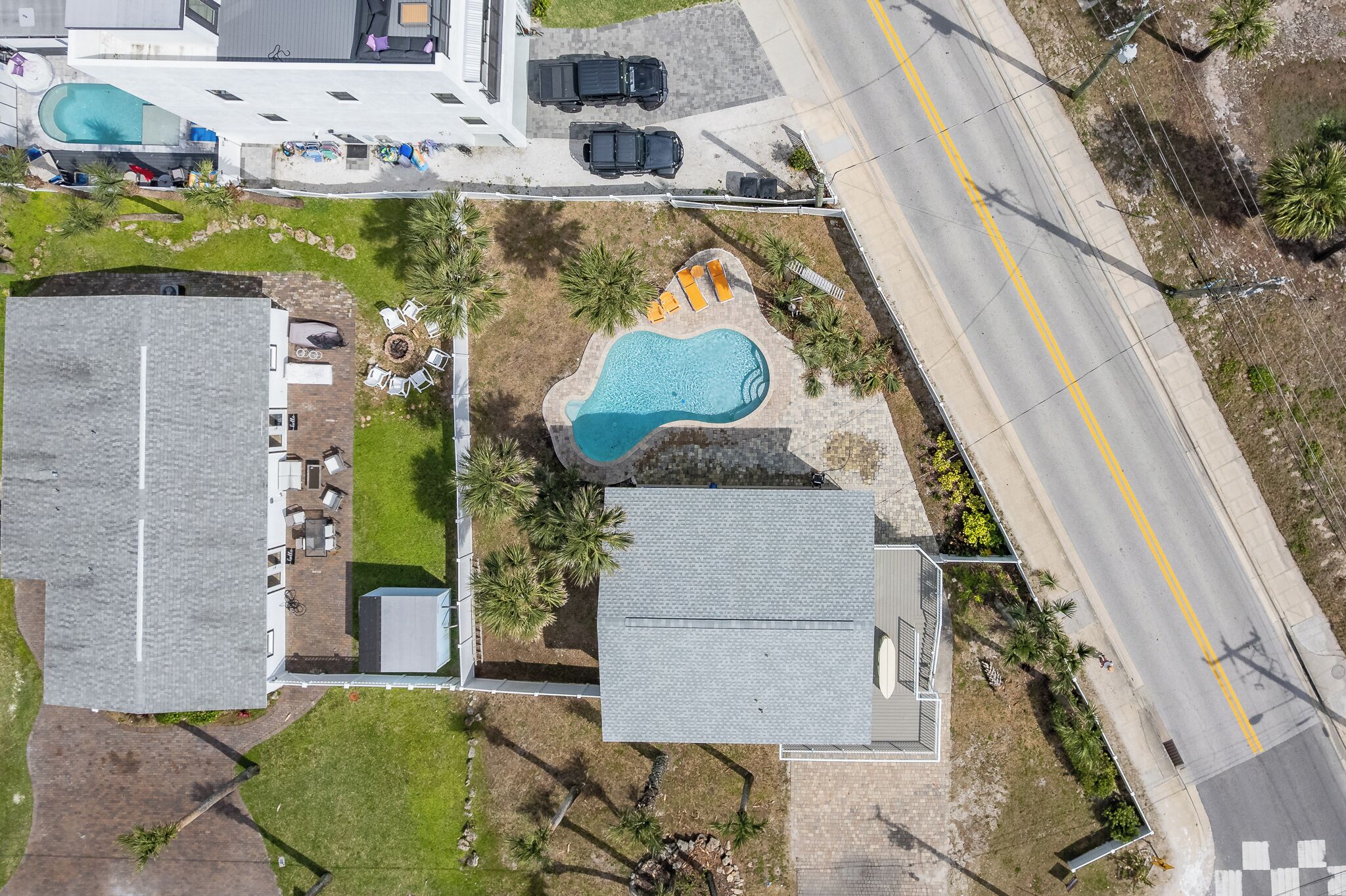 Vista aérea de una propiedad con piscina, zona de estacionamiento y camino.