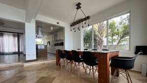 Una cucina moderna con mobili bianchi, un'isola centrale e un'area pranzo con tavolo in legno e sedie nere.