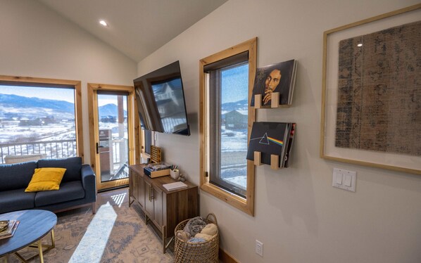 A living room with a sofa, TV, and framed items on the wall. - Mountain-View 3BR, Heated Gear Garage, Dogs Welcome, EV Outlet, 5 Min to Town (Crested Butte)