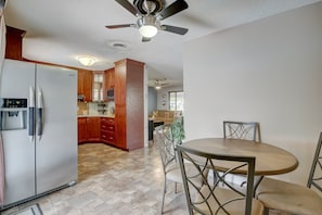 Una cocina moderna con refrigerador empotrado, armarios de madera y un comedor con una mesa redonda y sillas.