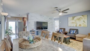 Un salon moderne avec une table en marbre, des sièges confortables, un téléviseur à écran plat et un ventilateur de plafond.