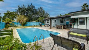 Un jardin avec une piscine, du mobilier d’extérieur et une maison.