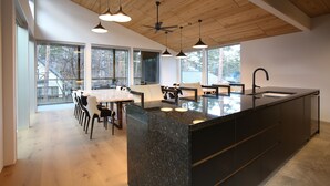 A modern kitchen with a large island, pendant lighting, and a ceiling fan.
