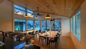 A spacious conference room with a large table, multiple chairs, and pendant lighting.
