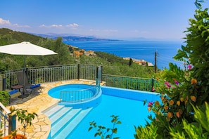 A swimming pool with a stone deck and a view of the sea. - Old Stone House in Nisaki (Corfu)