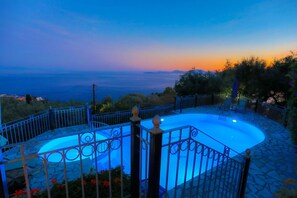 A pool with a metal fence and a view of the sea at dusk. - Old Stone House in Nisaki (Corfu)