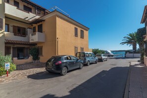 A street with parked cars and a building with balconies. - Piazzetta Bilo Porto 50m From The Beach (Loiri Porto San Paolo)