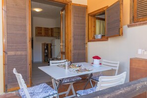 A dining area with a table, chairs, and a view into the kitchen. - Piazzetta Bilo Porto 50m From The Beach (Loiri Porto San Paolo)