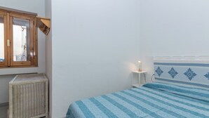 A bedroom with a bed, a bedside table, a mirror, and a radiator. - Piazzetta Bilo Porto 50m From The Beach (Loiri Porto San Paolo)