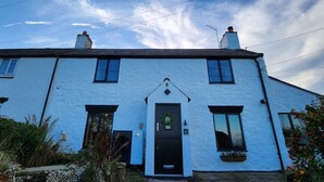 A white building with a black door, two chimneys, and a number '3' sign. - 3 Penllan Cottages (Holywell)