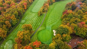 An aerial view of a golf course surrounded by autumn-colored trees. - Cozy Spacious Luxury Home with lots of Positivity Energy! (Tobyhanna)