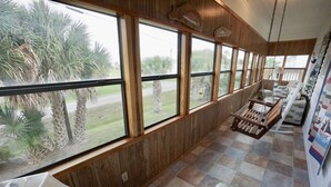 A room with large windows, wooden walls, and a swing chair. - GENTLE BREEZE is Close to Beach in POC (Port O Connor)
