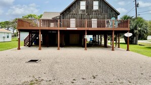 A wooden building with a balcony, a gravel driveway, and a clear sky. - GENTLE BREEZE is Close to Beach in POC (Port O Connor)