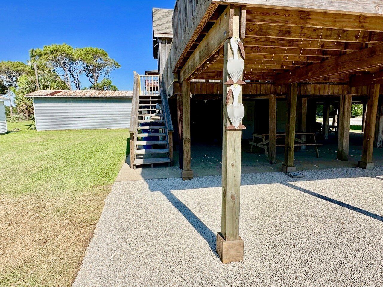 A wooden structure with a covered porch and a staircase leading to an upper level.