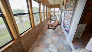 A room with large windows, a wooden bench, and a quilted wall hanging. - GENTLE BREEZE is Close to Beach in POC (Port O Connor)