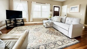 Un salon avec un canapé, un téléviseur et un tapis à motifs.