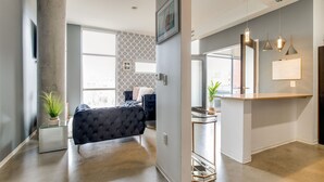 Quarto de hotel moderno com uma cama grande, uma mesa de centro de vidro e vista para a cidade.
