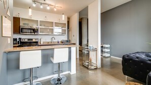 Uma cozinha moderna com uma ilha central, banquetas e um exaustor de aço inoxidável.