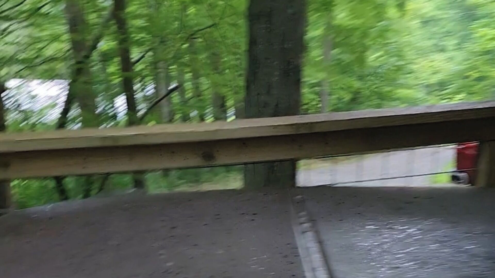 Vue de l’intérieur d’un véhicule, à travers une fenêtre, sur une route bordée d’une glissière de sécurité et avec des arbres en arrière-plan.