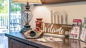 A reception desk with a lamp, a welcome sign, a basket with a camera, and brochures.