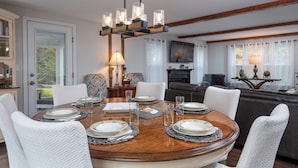 A dining area with a round table set for four, surrounded by white upholstered chairs.