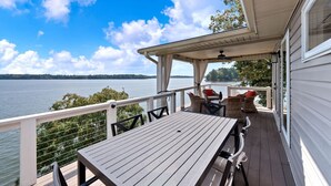 Une terrasse couverte, dotée d’une table et de chaises, qui offre une vue sur un lac.
