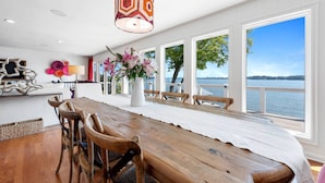 Un coin repas avec une table en bois, des chaises, un vase de fleurs et une vue sur un lac.