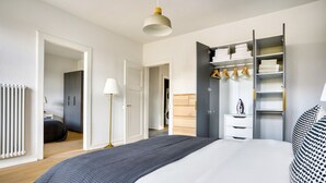 A modern bedroom with a large bed, a walk-in closet, and a radiator. - Airy Vorstädte 3.5 Room w/ W/D & Storage, 2 min to Market, by Blueground (Basel)